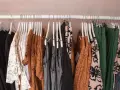 Ubrania na wieszakach: czarne, białe z czarnym wzorem, pomarańczowe, szare, zielone. To co to jest halfprice? To okazja na stylowe zakupy!