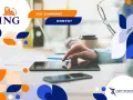 Jak zamknąć konto w ING? Na zdjęciu dłoń dotyka ekranu tabletu, obok leży smartfon i kubek kawy.