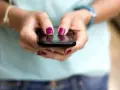 Dłonie z malowanymi paznokciami piszą na telefonie, być może ustawiając ipko zmiana limitu przelewu.
