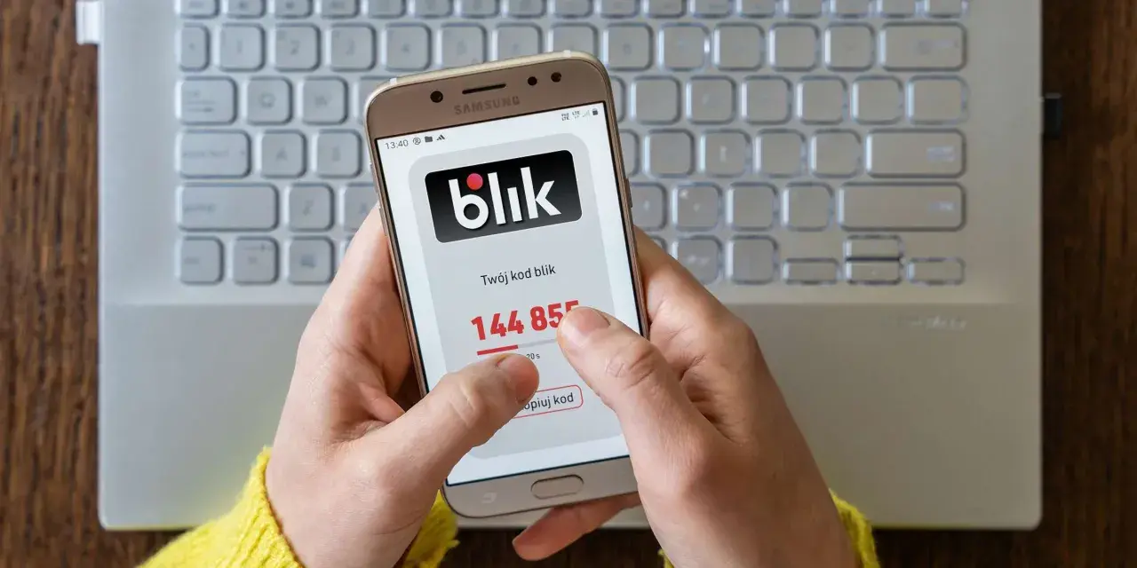 Ręce trzymają telefon z aplikacją Blik, na ekranie widoczny kod. Zastanawiasz się, jak cofnąć Blik? Ten obraz pokazuje, jak szybko uzyskać kod.