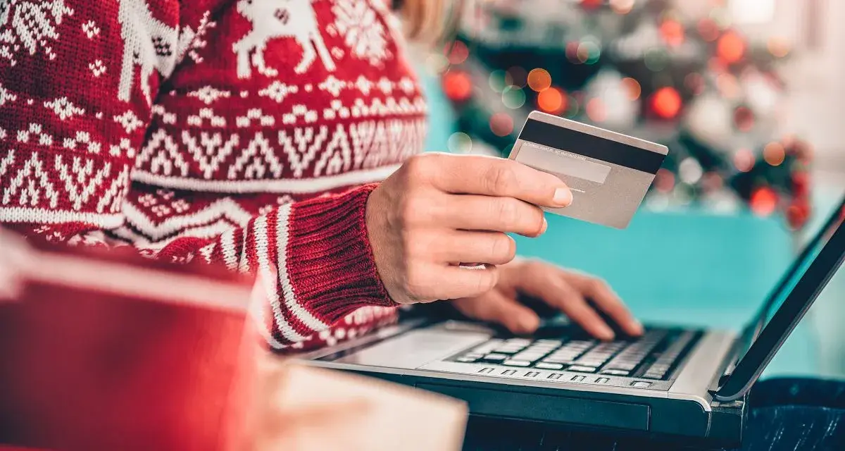 Karta kredytowa czy limit odnawialny? W świątecznym swetrze, z prezentami obok, kupuje online.