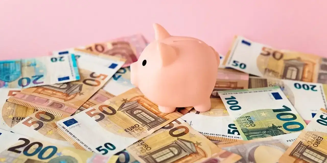 Różowa świnka-skarbonka na stosie banknotów euro. Zastanawiasz się nad oprocentowaniem konta walutowego?