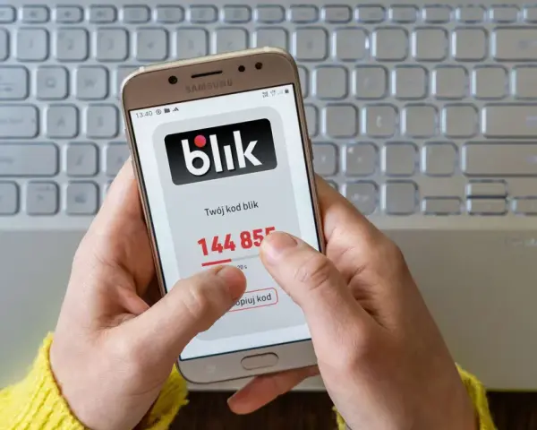 Ręce trzymają telefon z aplikacją Blik, na ekranie widoczny kod. Zastanawiasz się, jak cofnąć Blik? Ten obraz pokazuje, jak szybko uzyskać kod.