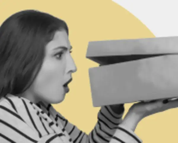 Zaskoczona kobieta otwiera pudełko z zakupami. Czy to prezent? GFK moje zakupy.
