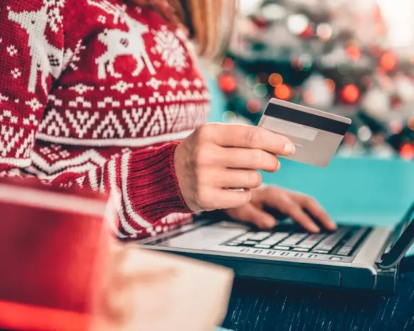 Karta kredytowa czy limit odnawialny? W świątecznym swetrze, z prezentami obok, kupuje online.