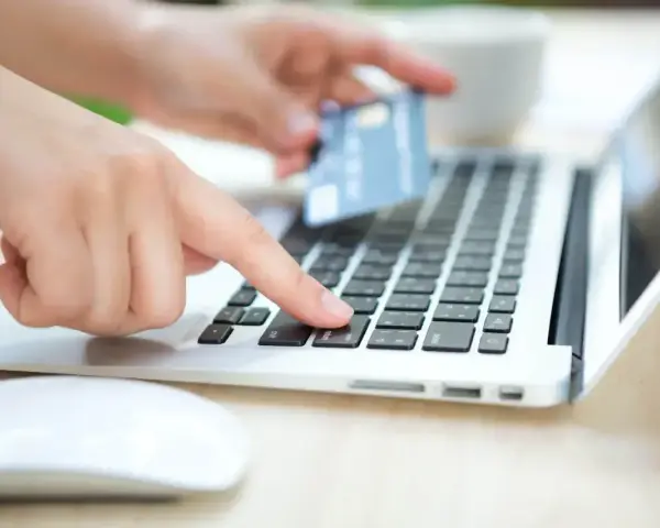 Dłonie wprowadzają dane karty na laptopie, zastanawiając się, czy Skrill jest bezpieczny.