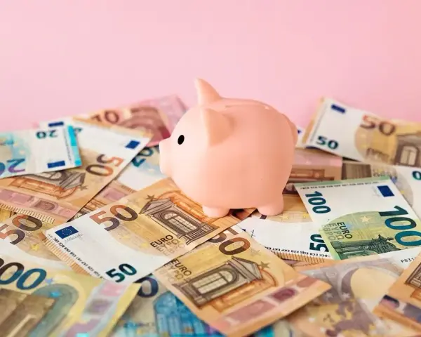 Różowa świnka-skarbonka na stosie banknotów euro. Zastanawiasz się nad oprocentowaniem konta walutowego?