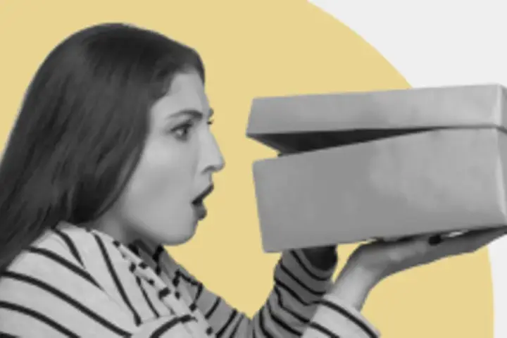 Zaskoczona kobieta otwiera pudełko z zakupami. Czy to prezent? GFK moje zakupy.