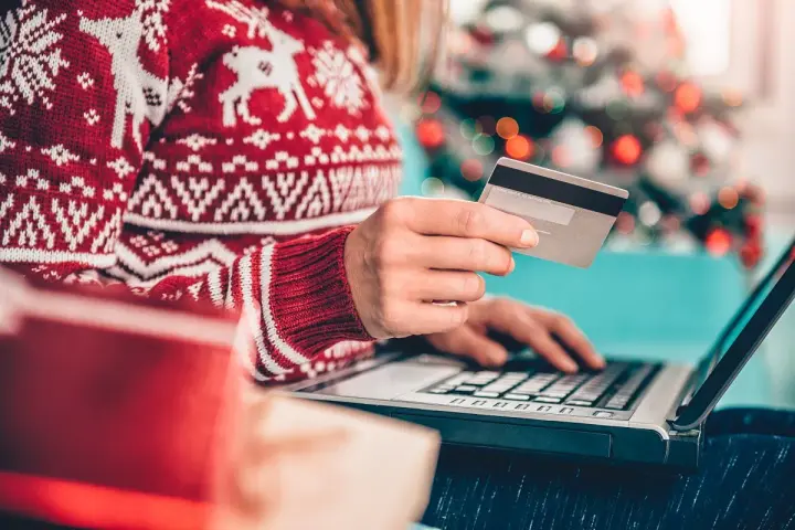 Karta kredytowa czy limit odnawialny? W świątecznym swetrze, z prezentami obok, kupuje online.
