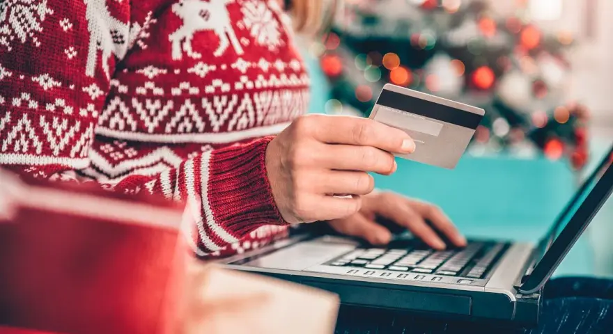 Karta kredytowa czy limit odnawialny? W świątecznym swetrze, z prezentami obok, kupuje online.