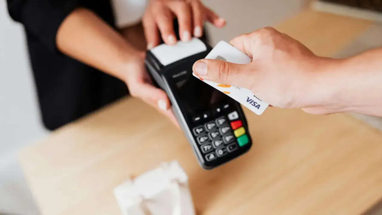 Zbliżenie na płatność zbliżeniową kartą Visa na terminalu. Globalne transakcje stają się prostsze.