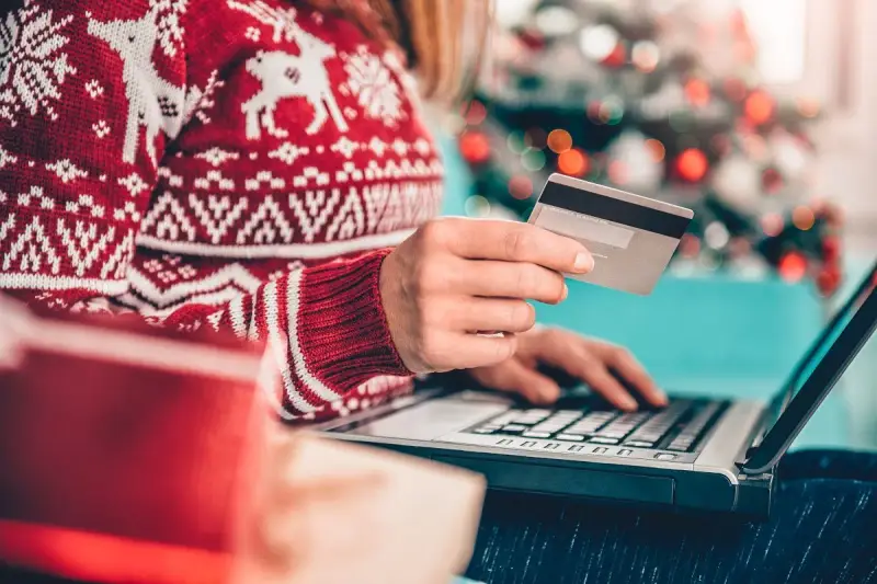 Karta kredytowa czy limit odnawialny? W świątecznym swetrze, z prezentami obok, kupuje online.